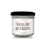 a glass jar with a black lid that says smells like kitty biscuits