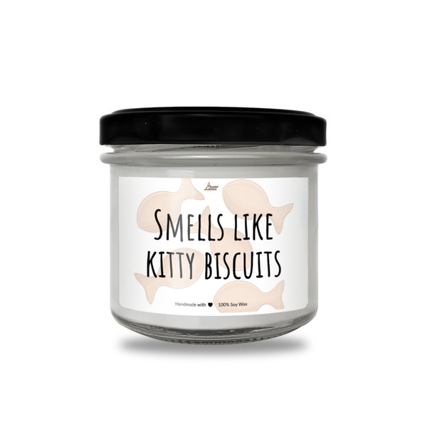 a glass jar with a black lid that says smells like kitty biscuits