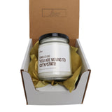 a white candle in a box with a brown ribbon around it