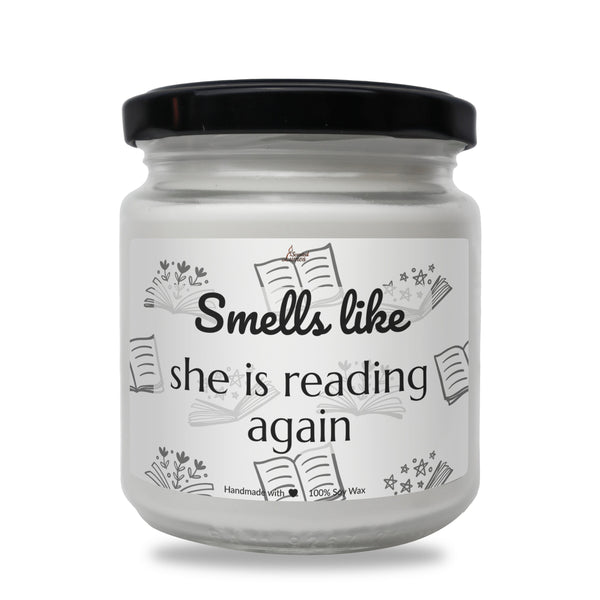 a white jar with a black lid that says smell like she is reading again