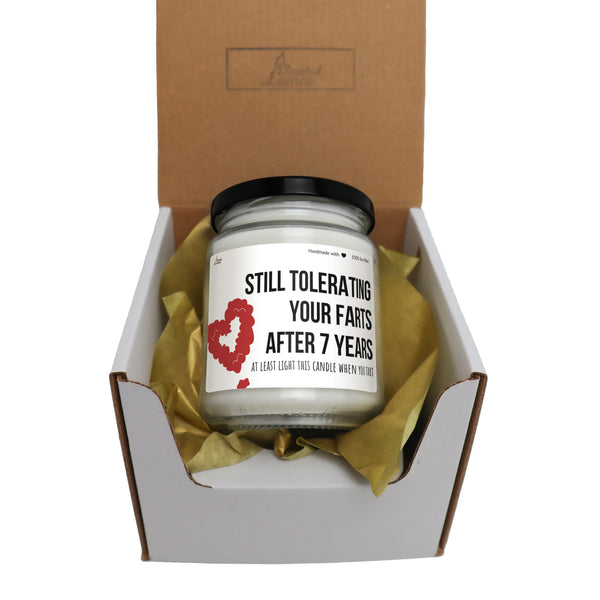 a candle in a box with a ribbon around it