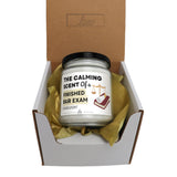 a candle in a box with a gold ribbon around it