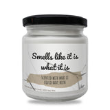 a white jar with a black lid that says smells like it is what it is