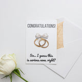 a white rose and two wedding rings on a card
