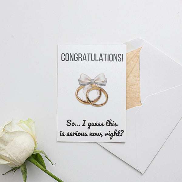 a white rose and two wedding rings on a card