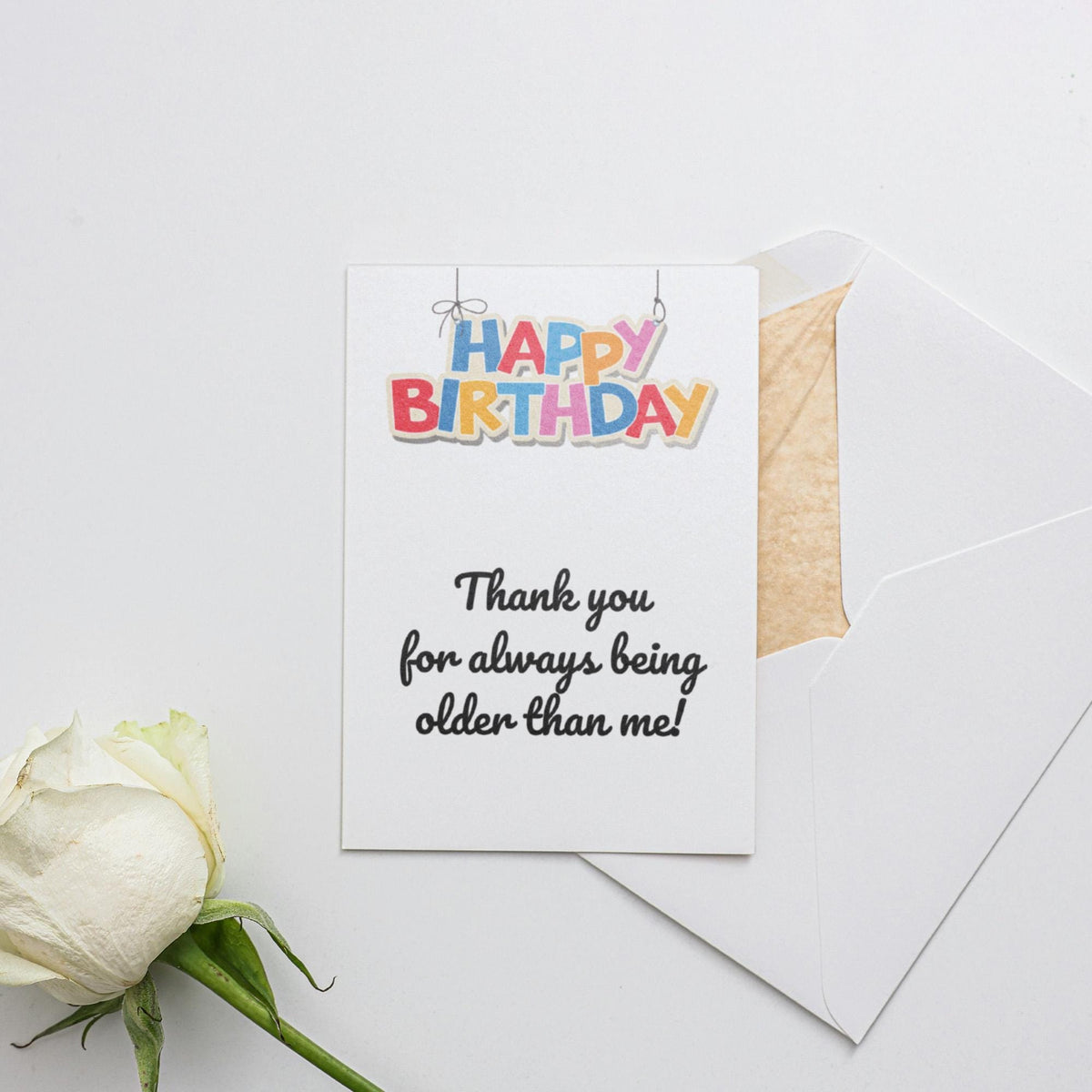 a white rose sitting next to a piece of paper