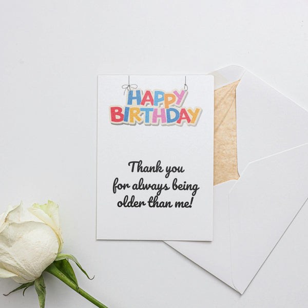 a white rose sitting next to a piece of paper