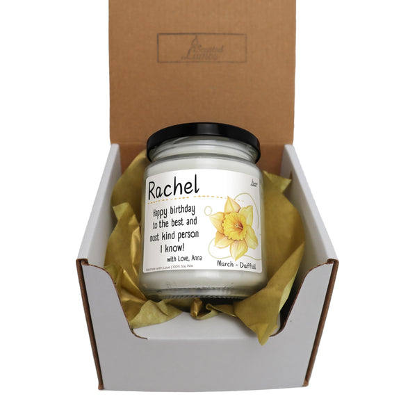 a candle in a box with a yellow ribbon around it